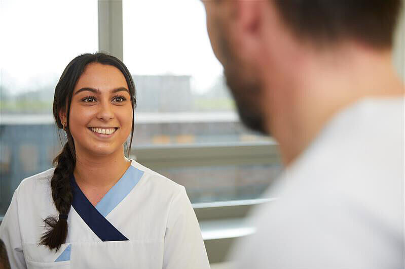 Pflegekonzept 2.0 der BG Kliniken Krankenschwester von vorne im Gespräch mit Mann (im Anschnitt)