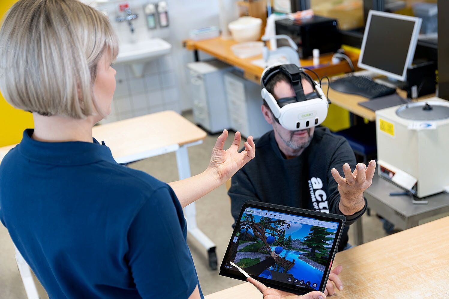 Therapeutin mit Tablet, Patient mit VR-Brille
