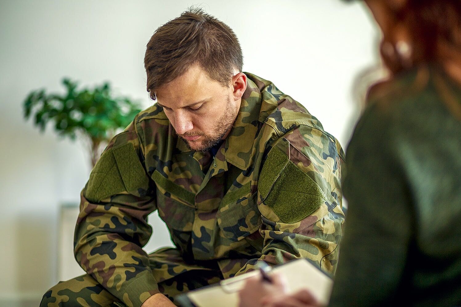 (Bildnachweis: KatarzynaBialasiewicz/iStock.com) Soldat in einer Gesprächs- und Behandlungssituation