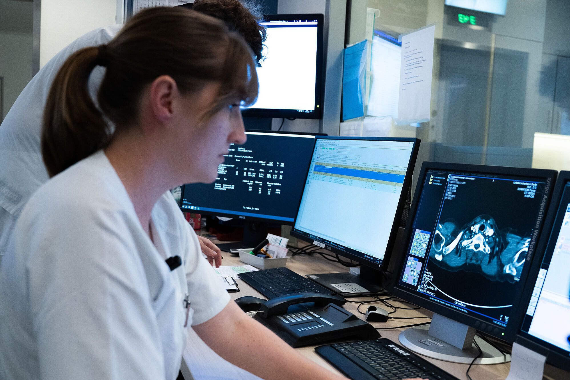 Frau sitzt in der Klinik vor einem Computerbildschirm mit Röntgenbildern