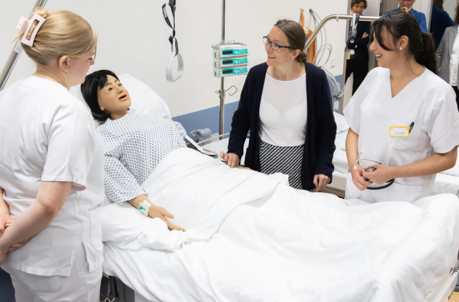 Schülerinnen üben pflegerische Aufgaben an einer Puppe.